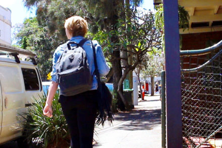 girl walking along a Sydney pavement with a backpack on