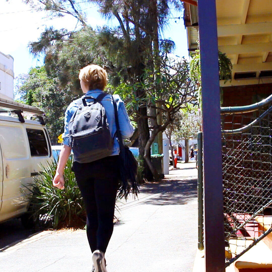 girl walking along a Sydney pavement with a backpack on