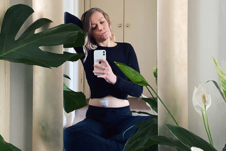 Jen Grieves sitting on the floor taking a selfie in a mirror with an Omnipod insulin pump visible on her torso