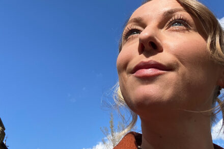 Jen Grieves looking up with a bright blue sky behind her